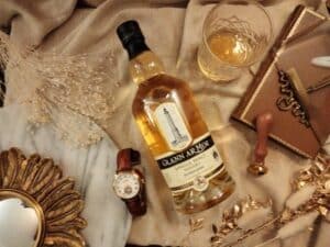 Bouteille de whisky dans un joli décor, avec un verre, un sceau, une montre, des bijoux