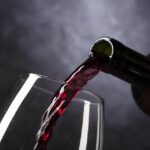 Bouteille de vin rouge avec un verre, symbolisant ses bienfaits pour le cœur.